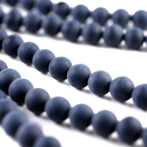May include: A strand of dark blue round beads, made of a matte material, strung together to form a necklace or bracelet.