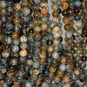 Puede incluir: Una hebra de cuentas redondas de ágata multicolores. Las cuentas son una mezcla de marrón, gris y blanco con una calidad translúcida. Las cuentas tienen un diámetro aproximado de 6 mm.