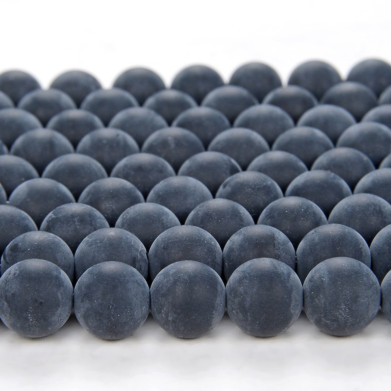 May include: A close-up of a group of dark gray round beads arranged in a grid pattern. The beads are smooth and have a matte finish.