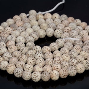 May include: A strand of white and brown seed beads, each bead has a speckled pattern.