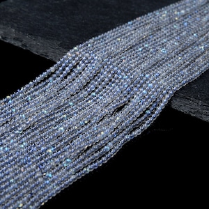 May include: A strand of iridescent white and blue gemstone beads. The beads are round and have a smooth, polished finish.