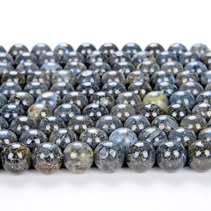 Könnte beinhalten: Nahaufnahme einer Sammlung runder, schwarz-goldfarbener Perlen. Die Perlen haben eine marmorierte, gefleckte Optik.