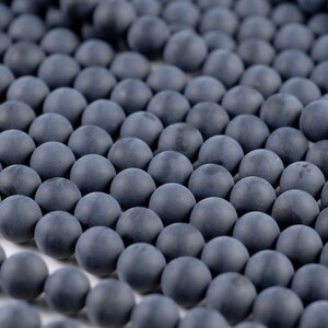 May include: A strand of dark gray round beads. The beads are smooth and matte.
