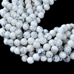 May include: A strand of white howlite beads with black veining. The beads are round and smooth, and they are strung together on a clear thread.