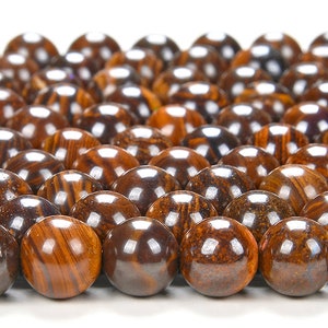 May include: A close-up of a pile of round, brown and black gemstone beads. The beads have a striated pattern and a glossy finish.