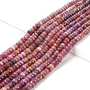 May include: A strand of pink and red faceted gemstone beads. The beads are round and have a slightly irregular shape. The beads are strung on a clear thread.