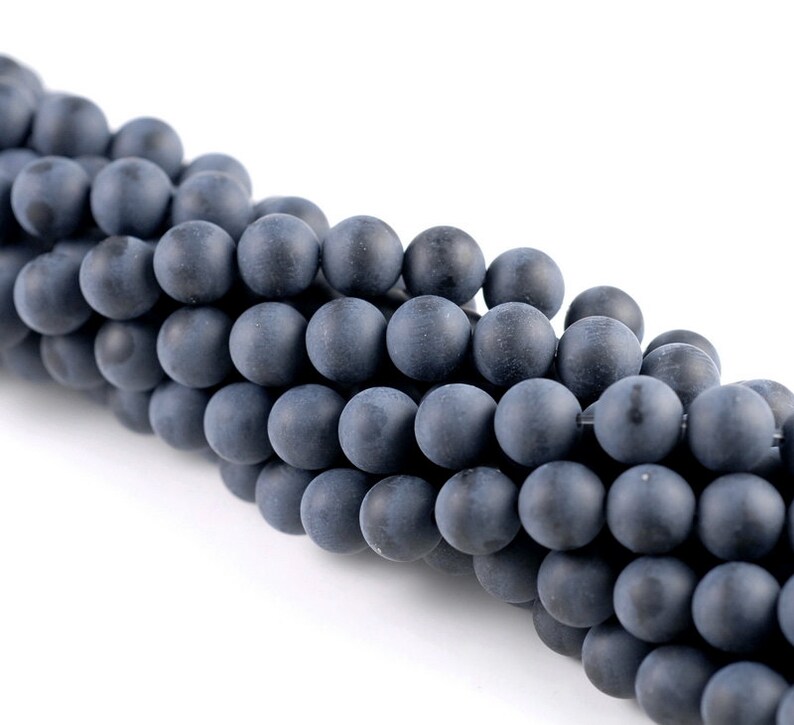 May include: A strand of dark gray matte round beads. The beads are smooth and have a slightly textured surface.