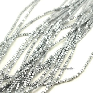 May include: A strand of silver-toned faceted beads. The beads are small and have a hexagonal shape. The beads are strung on a clear thread.
