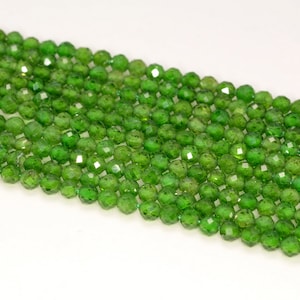 May include: A strand of green gemstone beads. The beads are faceted and have a round shape.