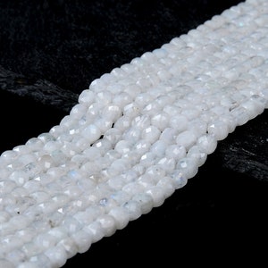 May include: A strand of white moonstone beads, faceted and oval shaped. The beads are strung together and have a smooth, polished finish.