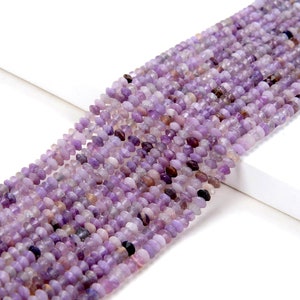 May include: A strand of purple amethyst beads, each bead is faceted and has a slightly irregular shape. The beads are strung together on a clear thread.