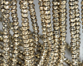 May include: A strand of gold-toned faceted beads. The beads are small and round, with a shiny, metallic finish.