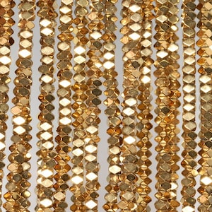 Peut inclure: Un brin de perles facettées dorées. Les perles sont petites et de forme hexagonale.