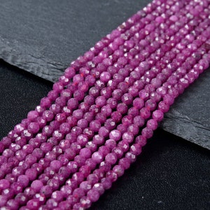May include: A strand of pink faceted gemstone beads. The beads are round and have a smooth, polished finish.