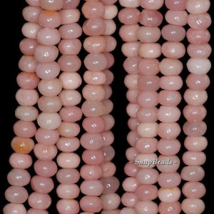 May include: A strand of pink opal beads, each bead is smooth and round. The beads are strung together on a clear thread. The beads are approximately 6mm in diameter.