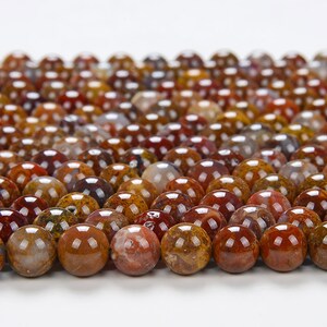 May include: A close-up of a strand of round, brown, red, and white agate beads. The beads are polished and have a smooth, glossy finish.