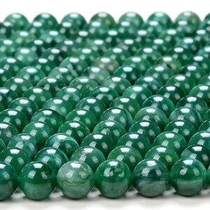 May include: A close-up view of a collection of round, green jade beads. The beads are smooth and polished, with a slight variation in colour and pattern.