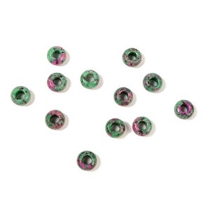 May include: A collection of eleven round, donut-shaped beads made of green zoisite with vibrant pink ruby inclusions. Each bead features a smooth, polished surface and a central hole, displaying a natural mottled pattern of green and pink tones.