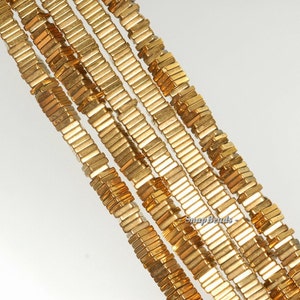 以下が含まれることがあります： 金色の正方形のビーズが、ジュエリー作りのために並んでいます。