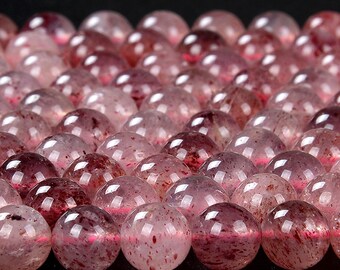 Könnte beinhalten: Nahaufnahme einer Reihe runder, durchscheinender rosa und roter Edelsteinperlen. Die Perlen haben ein gesprenkeltes, wolkiges Aussehen.