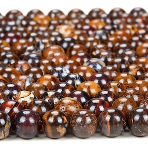 May include: A close-up of a collection of round, brown, and iridescent opal beads. The beads have a variety of patterns and colours, including brown, black, white, and blue.