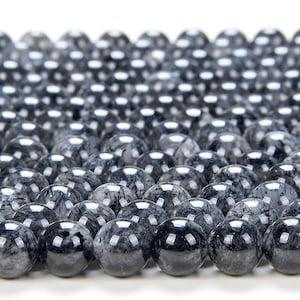 May include: A close-up of a collection of black and gray gemstone beads. The beads are round and have a smooth, polished finish. They are arranged in a close-packed pattern, creating a visually appealing texture.