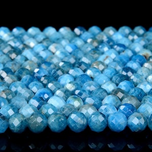 Op de afbeelding: Een close-up van een stapel blauwe edelsteen kralen. De kralen zijn gefacetteerd en hebben een lichtblauwe kleur. De kralen zijn in een verspringend patroon gerangschikt.
