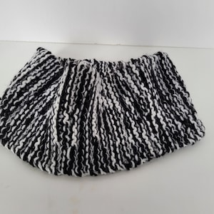 May include: Black and white striped knitted headband. The headband is made of a soft, chunky yarn.