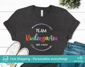 May include: A dark grey t-shirt with the text "TEAM Kindergarten MRS. KALINA" in a rainbow circle with arrows on either side.