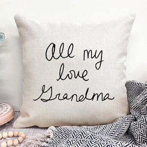May include: A beige throw pillow with black cursive text that reads "all my love Grandma".