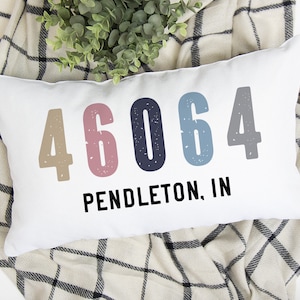 May include: White throw pillow with the numbers 46064 in different colors and the text "PENDLETON, IN" printed on it.