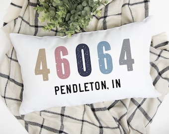 May include: White throw pillow with the numbers 46064 in different colors and the text "PENDLETON, IN" printed on it.