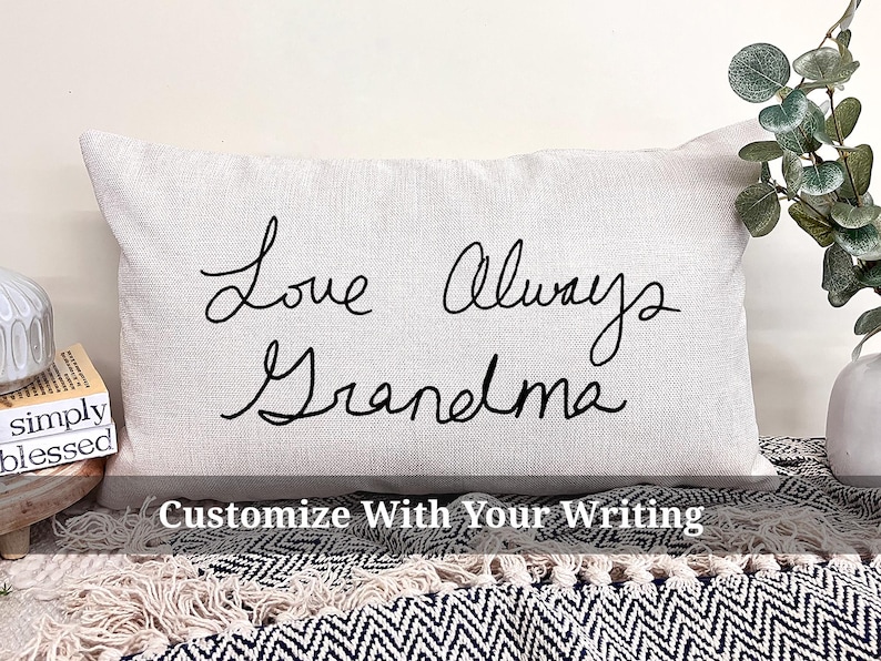 May include: A white pillow with black cursive writing that says "Love Always Grandma". The pillow is on a black and white patterned surface.