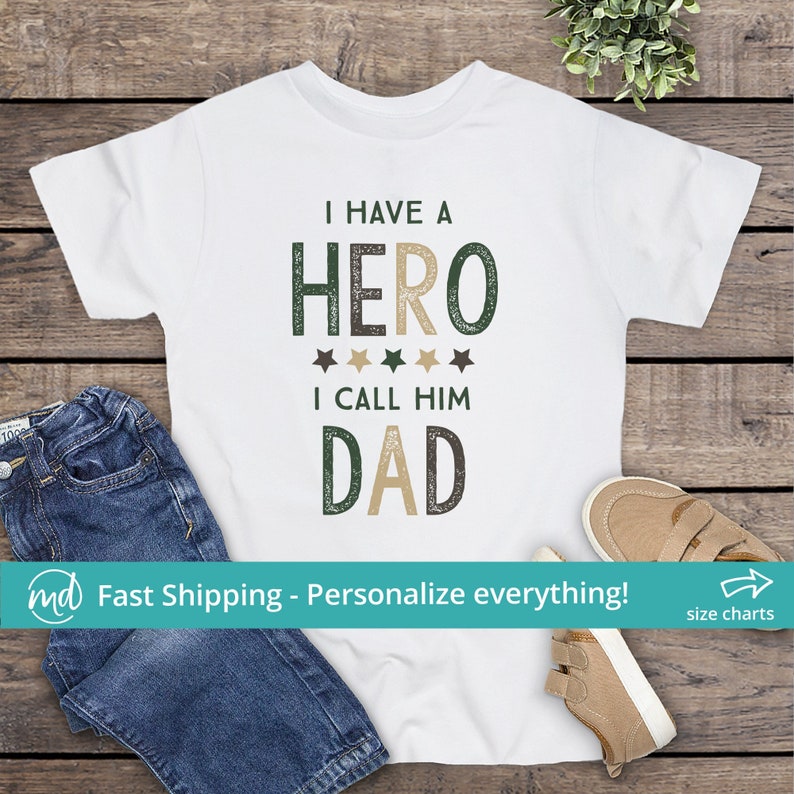 May include: White t-shirt with a green and brown graphic that says "I have a hero I call him dad".