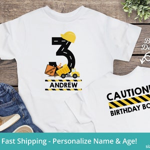 May include: A white t-shirt with a construction theme for a birthday. The front of the shirt has a yellow construction hat, a black number 3, a yellow dump truck, and the name "ANDREW". The back of the shirt has black text that says "CAUTION! BIRTHDAY BOY" with yellow and black stripes.