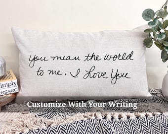 May include: A white throw pillow with black handwritten text that reads "You mean the world to me. I love you." The pillow is on a black and white patterned surface. The text "Customize With Your Writing" is below the pillow.