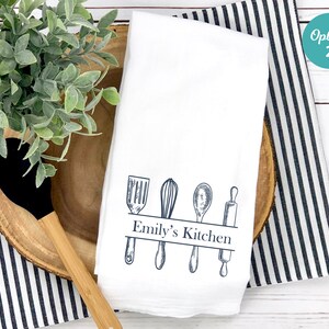 Puede incluir: Toalla de cocina blanca con un dise&ntilde;o azul de utensilios de cocina y el texto "Emily's Kitchen".