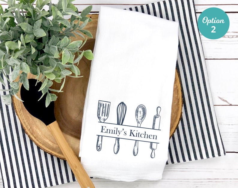 Puede incluir: Toalla de cocina blanca con un dise&ntilde;o azul de utensilios de cocina y el texto "Emily's Kitchen".