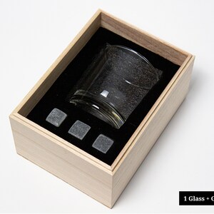 May include: A wooden gift box with a glass and four gray stone ice cubes inside. The box is open and the glass is visible. 1 Glass + Gift Box