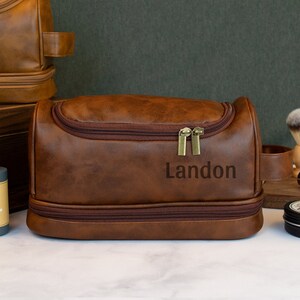 May include: Brown leather travel toiletry bag with a zipper closure and a personalized name, Landon, embossed on the front.