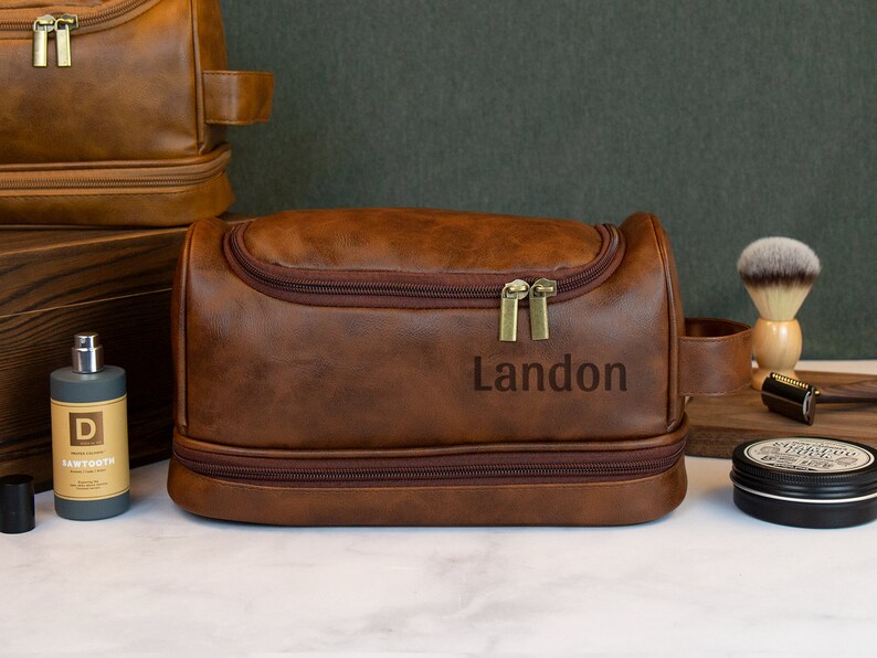 May include: Brown leather travel toiletry bag with a zipper closure and a personalized name, Landon, embossed on the front.