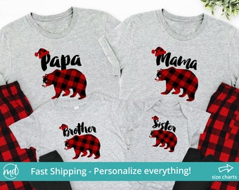 May include: Matching family pajamas with a gray background and red and black plaid bear design. The text on the shirts reads "Papa", "Mama", "Brother", and "Sister".