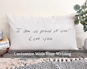 May include: A white pillow with the handwritten message "I am so proud of you!! Love you" on it. The pillow is on a black and white patterned surface.