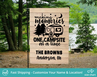 May include: A wooden camping themed yard sign with a black silhouette of a camper, trees, and stars. The text reads "Making Memories One Campsite at a Time The Browns Anderson, In".