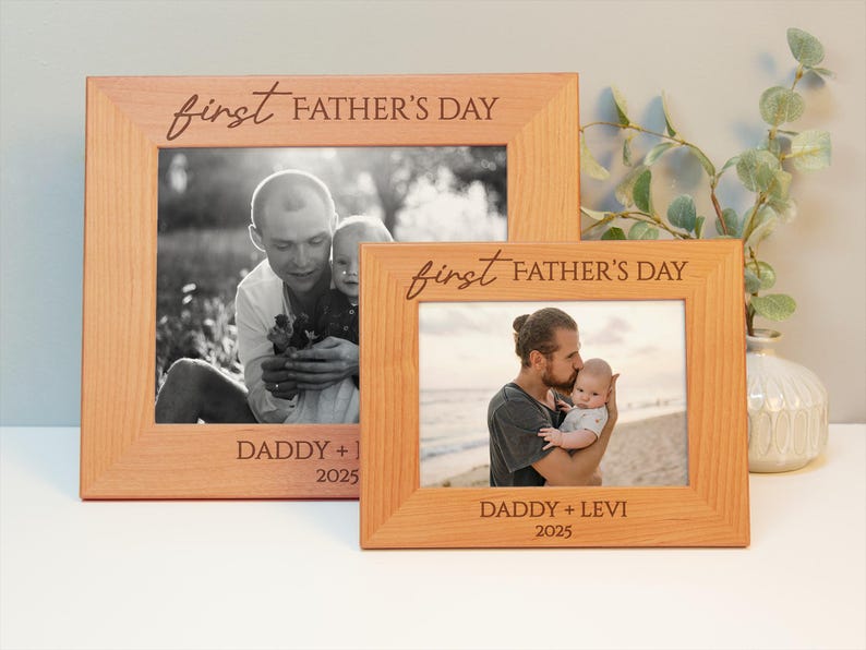 May include: Two light brown wooden photo frames. Each frame has a photograph of a father and child. The frames are inscribed with "first FATHER'S DAY" and "DADDY + [child's name] 2025". The frames are of different sizes.