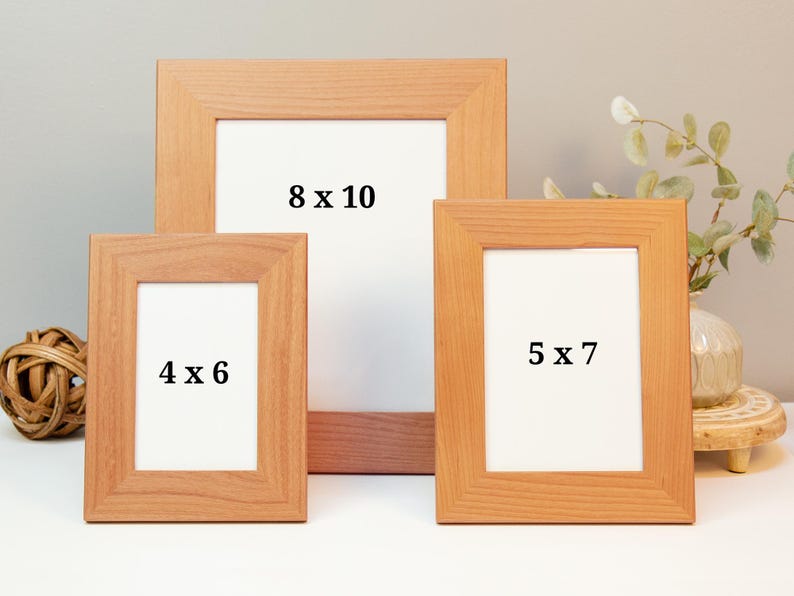 May include: Three wooden picture frames in varying sizes: 4 x 6 inches, 5 x 7 inches, and 8 x 10 inches. The frames are a light brown colour with white matting. The frames are displayed on a white surface.