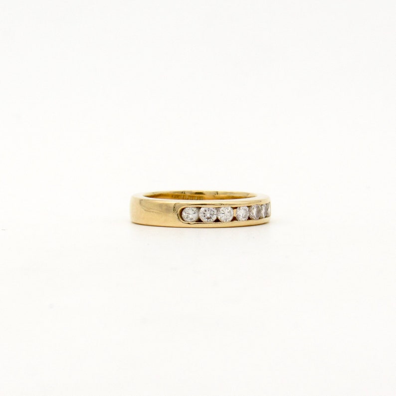 K&ouml;nnte beinhalten: Ein Goldring mit einer Reihe kleiner, klarer Diamanten, die in der Mitte eingesetzt sind.