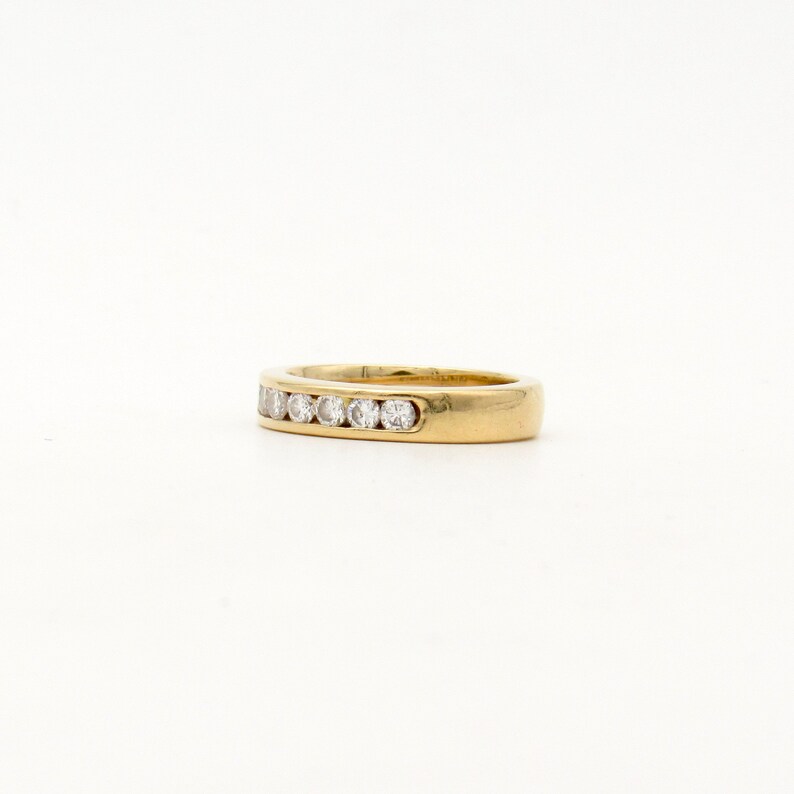 K&ouml;nnte beinhalten: Ein Goldring mit einer Reihe kleiner, klarer Diamanten, die in der Mitte eingesetzt sind.
