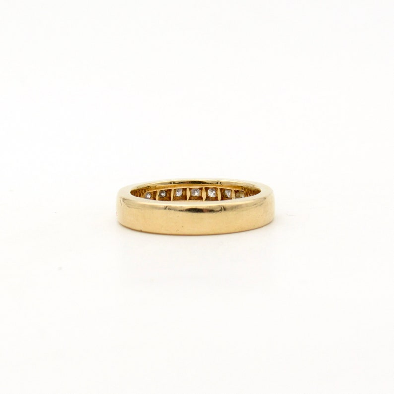 K&ouml;nnte beinhalten: Ein Goldring mit einer Reihe kleiner Diamanten, die in der Mitte eingesetzt sind.