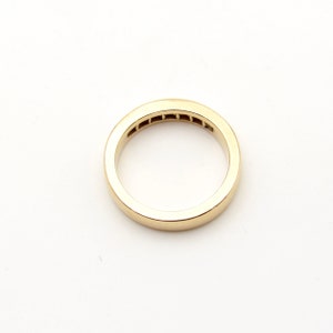 K&ouml;nnte beinhalten: Ein Goldring mit einer Reihe kleiner Diamanten, die in der Mitte eingesetzt sind.